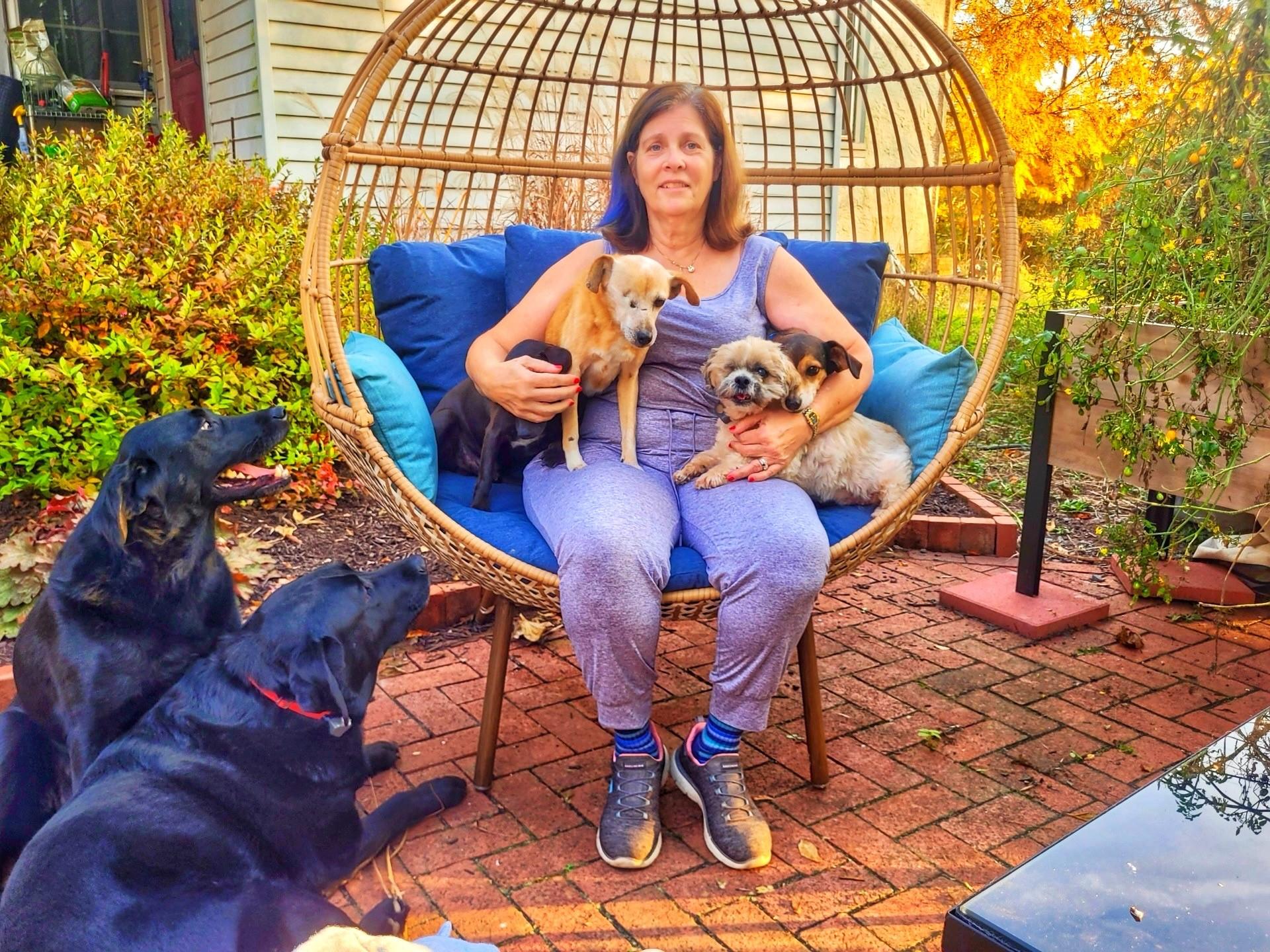 Ann B. posing with four dogs outside of her farmhouse
