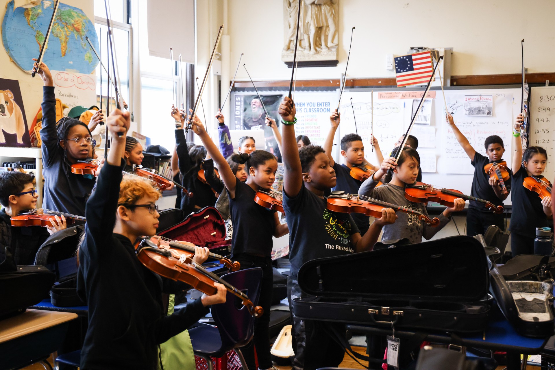 CMCB students holding violin sticks in air during class