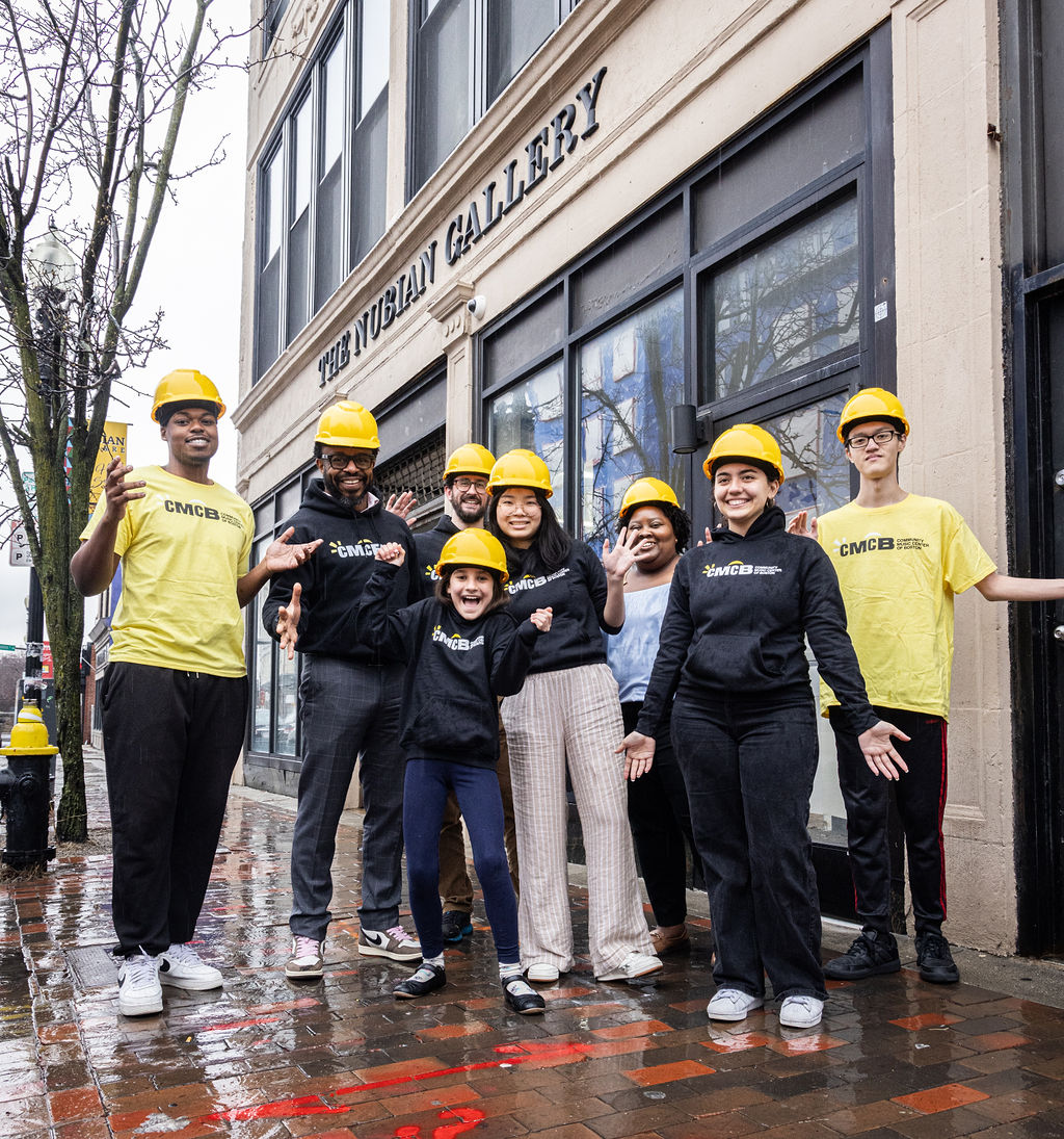 CMCB students posing with hard hats outside of The Nubian Gallery near new location
