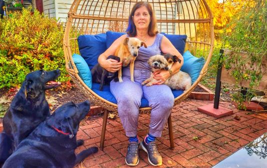 Ann B. posing with four dogs outside of her farmhouse